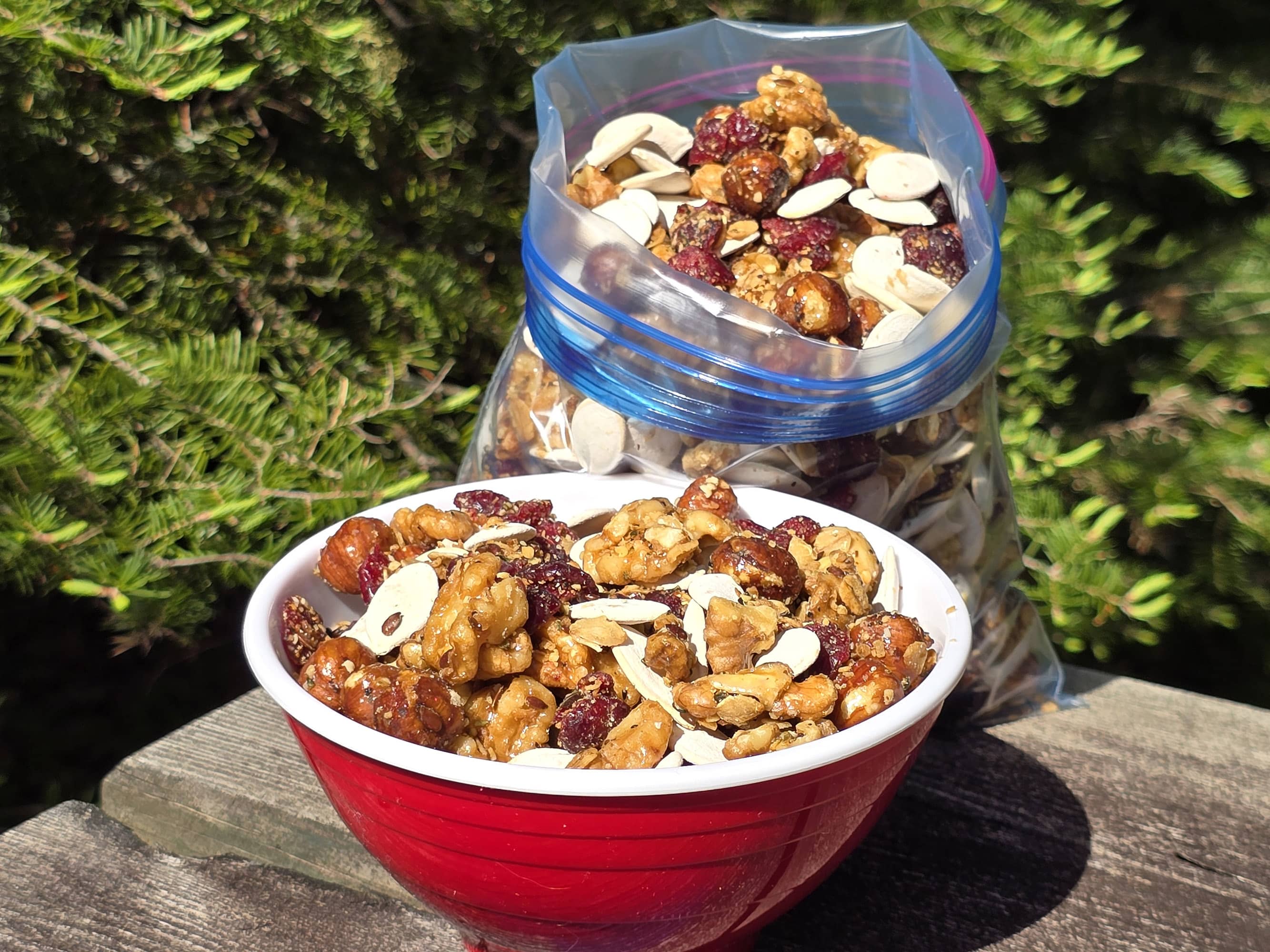 A bowl and a bag of Canada day trail mix, with maple glazed nuts, dried cranberries, maple granola, and pumpkin seeds.