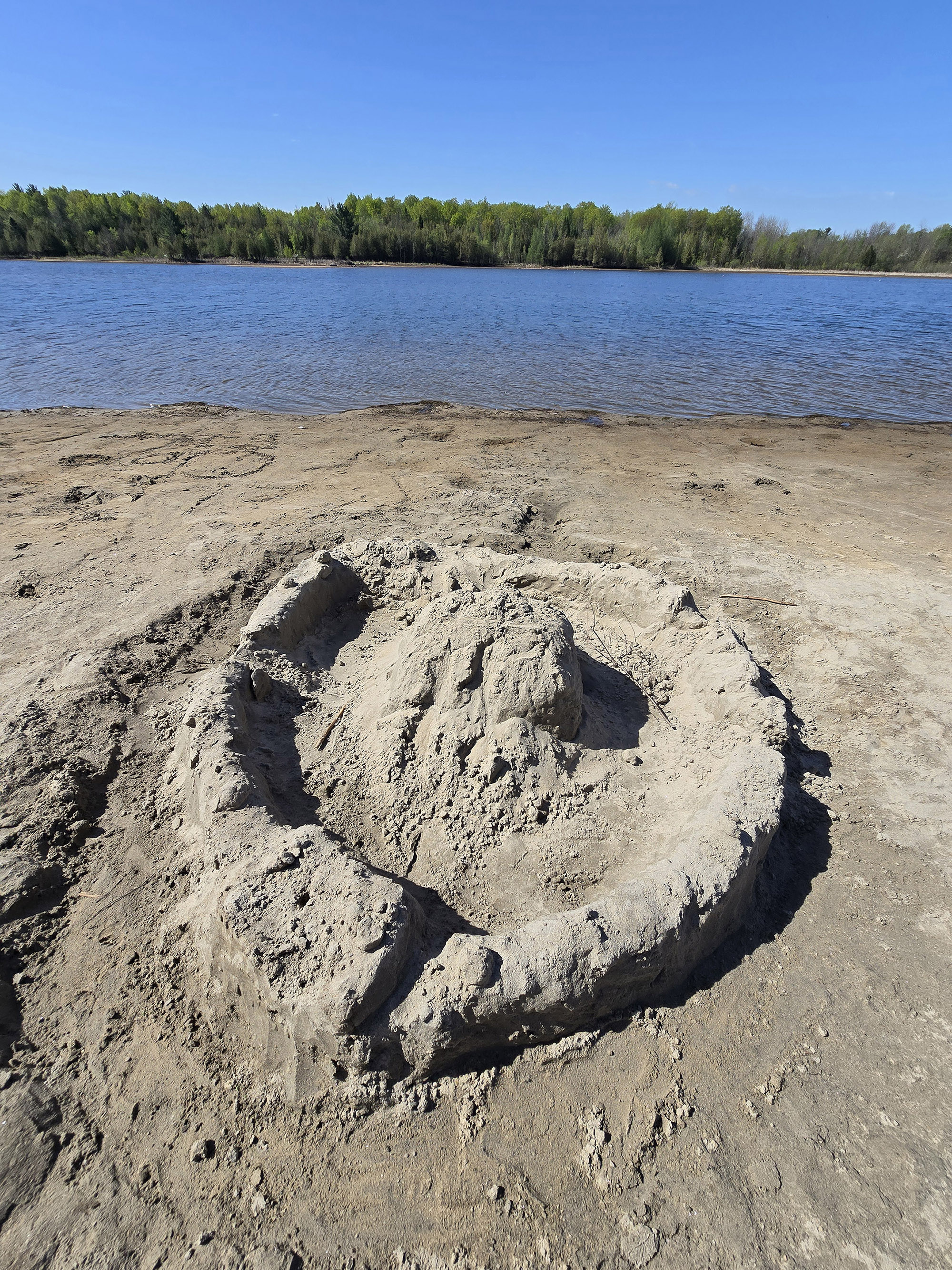 A large sandcastle on an ottawa river beach.