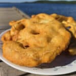 3 large pieces of Indian Fry bread on a plate, on a wooden dock.