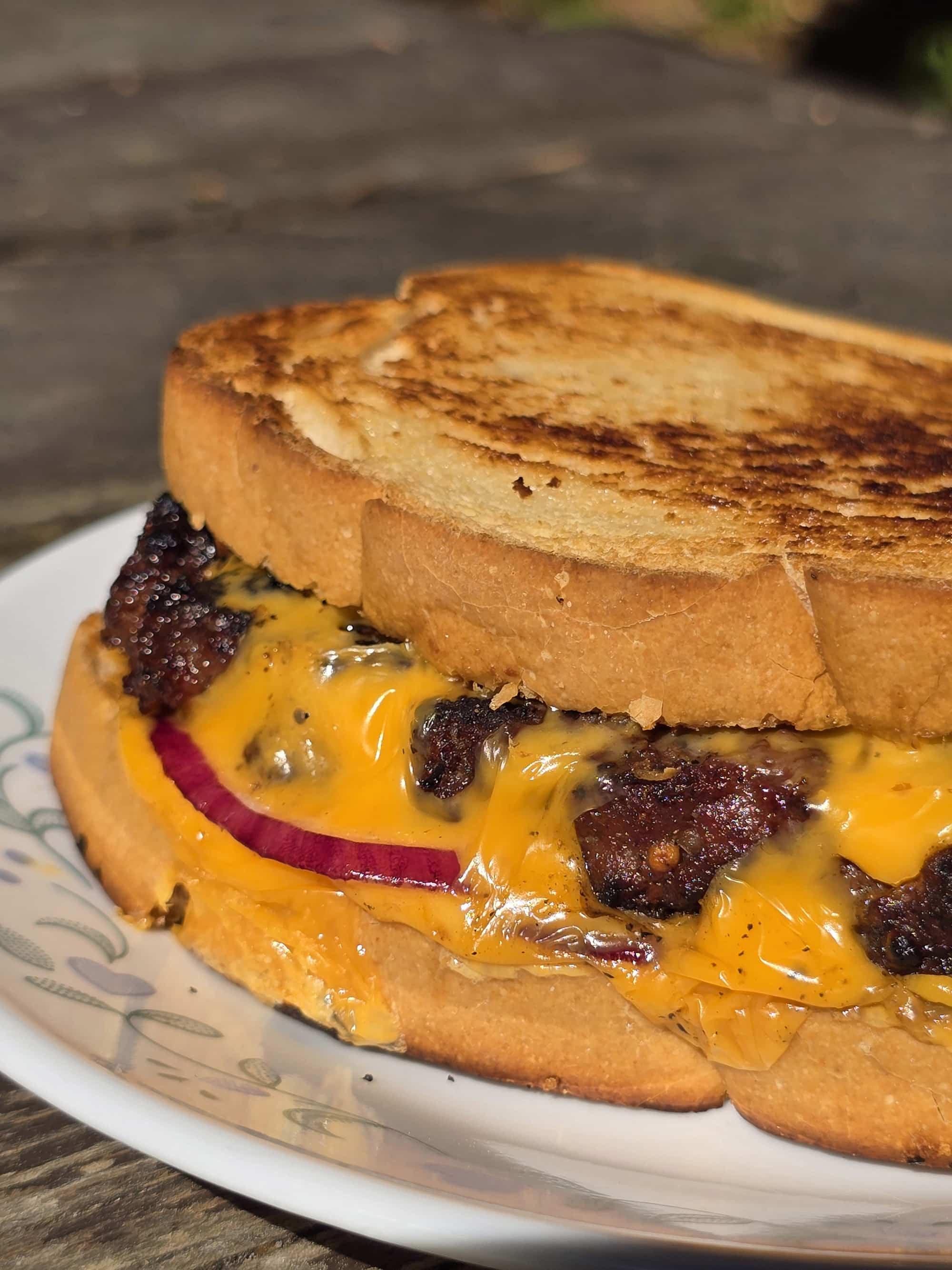 A grilled cheese cheeseburger on a plate.