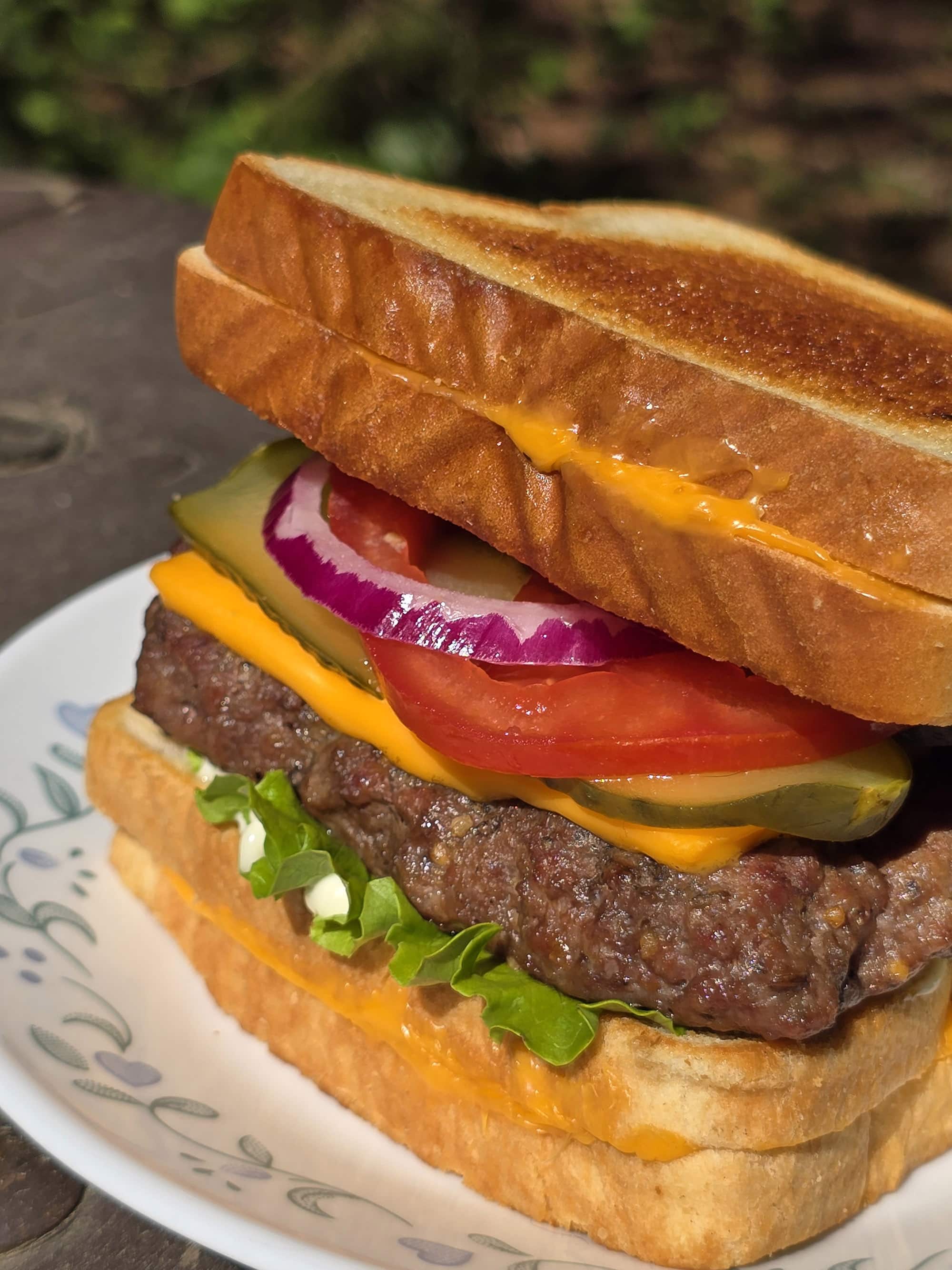 A grilled cheese cheeseburger made with a burger patty ad 2 grilled cheese sandwiches.