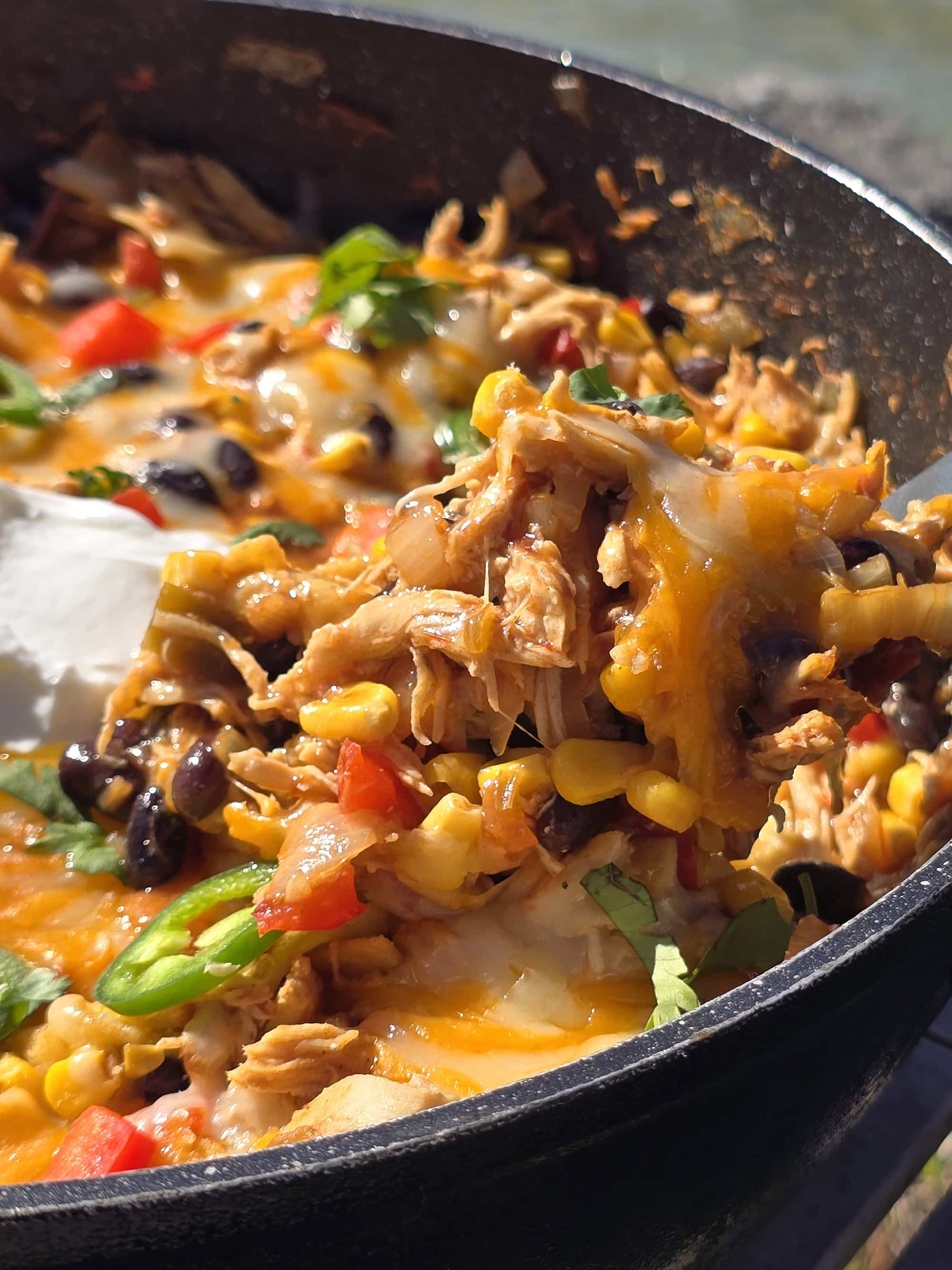 A pan of deconstructed enchilada skillet - red peppers, onions, corn, black beans, chicken, and enchilada sauce with cheese.