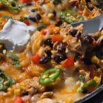A pan of deconstructed enchilada skillet - red peppers, onions, corn, black beans, chicken, and enchilada sauce with cheese.
