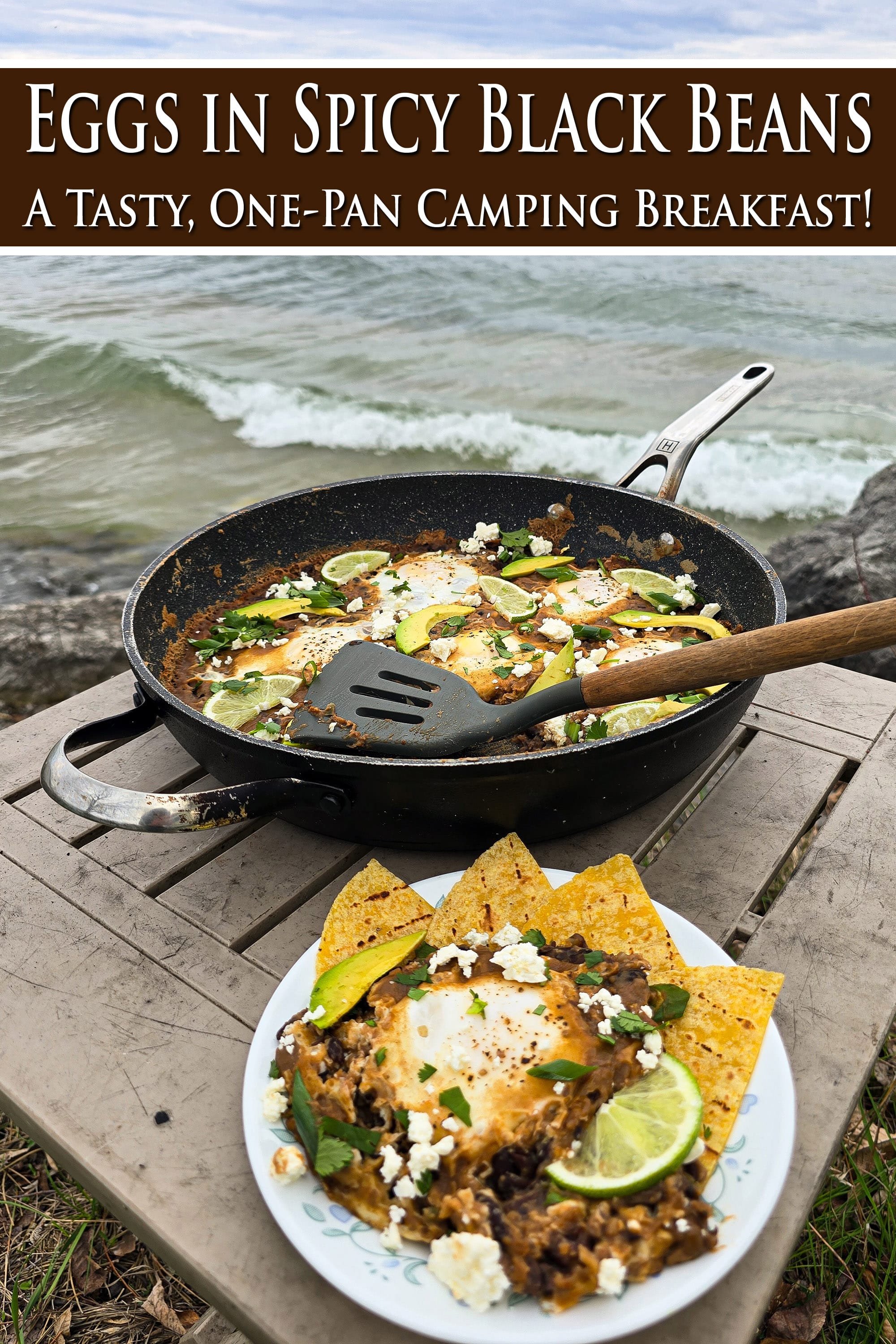 A pan of Huevos Enfrijolados, garnished with lime slices, avocado, cilantro, and crumbled queso fresco. Overlaid text says eggs in spicy black beans, a tasty one pan camping breakfast.