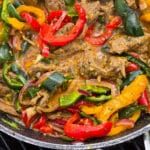 Steak Fajitas filling with marinated beef strips, multicoloured bell peppers, poblano peppers, and jalapeno in a skillet.