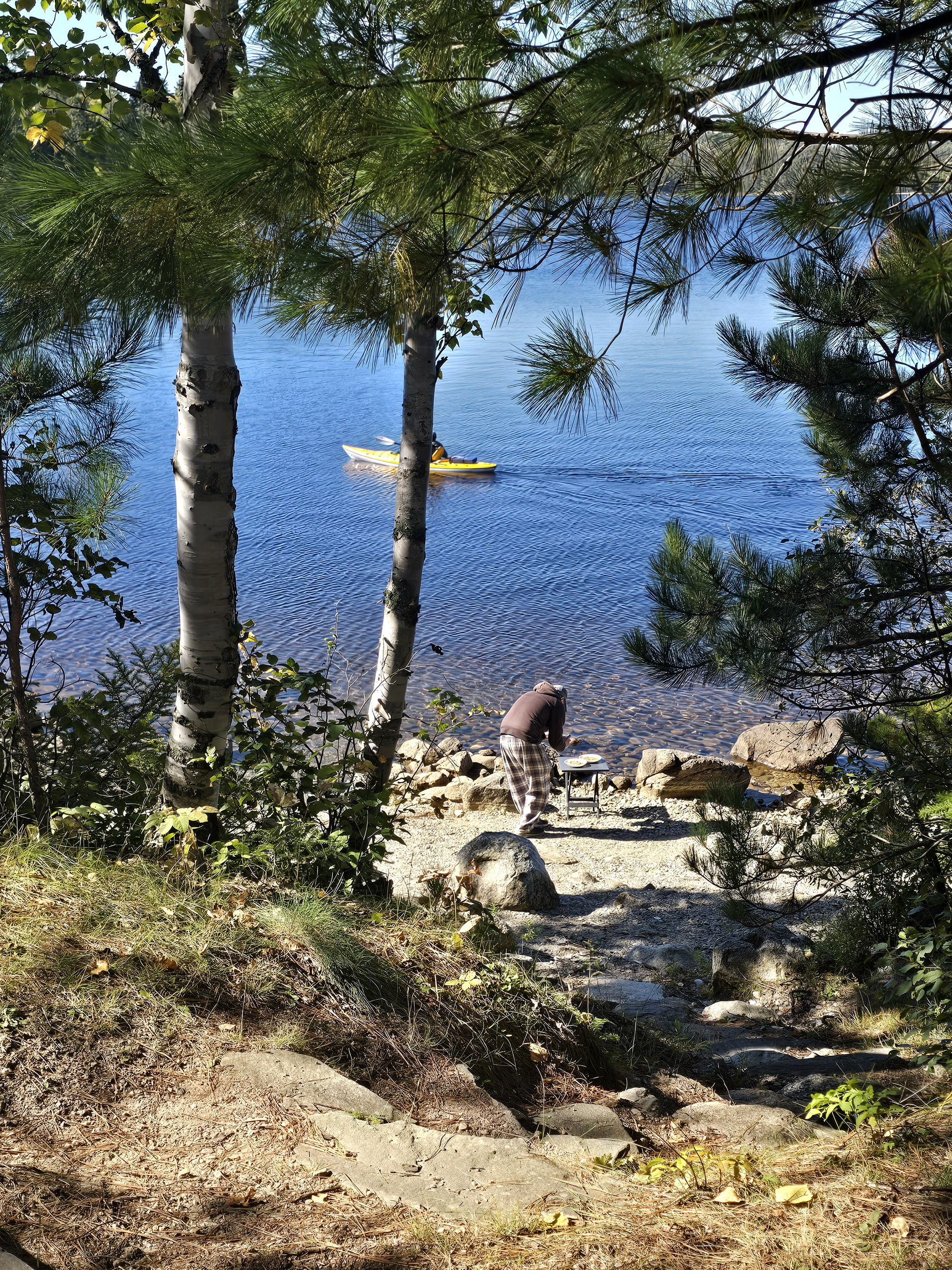 A man photographing pumpkin oatmeal on the shore of a lake.