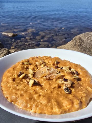 1 bowl of skillet pumpkin oatmeal garnished with pepitas, walnuts, and candied ginger.